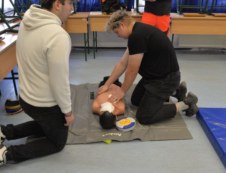CPR training session with a dummy in a classroom environment.
