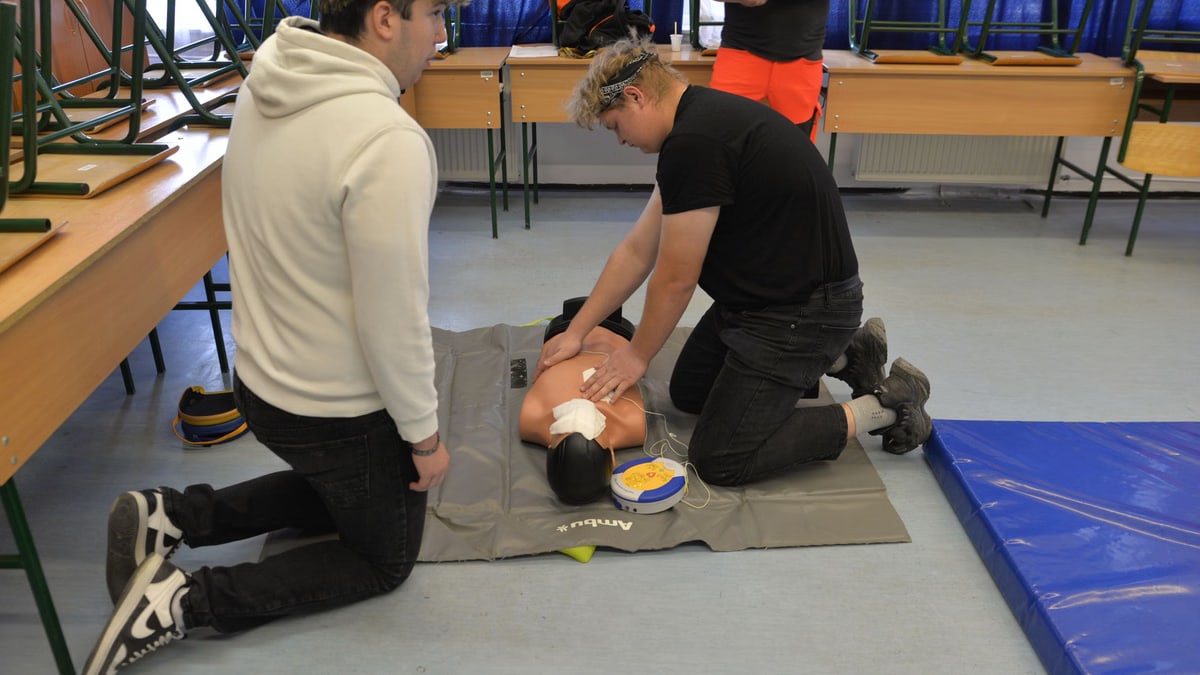 CPR training session with a dummy in a classroom environment.